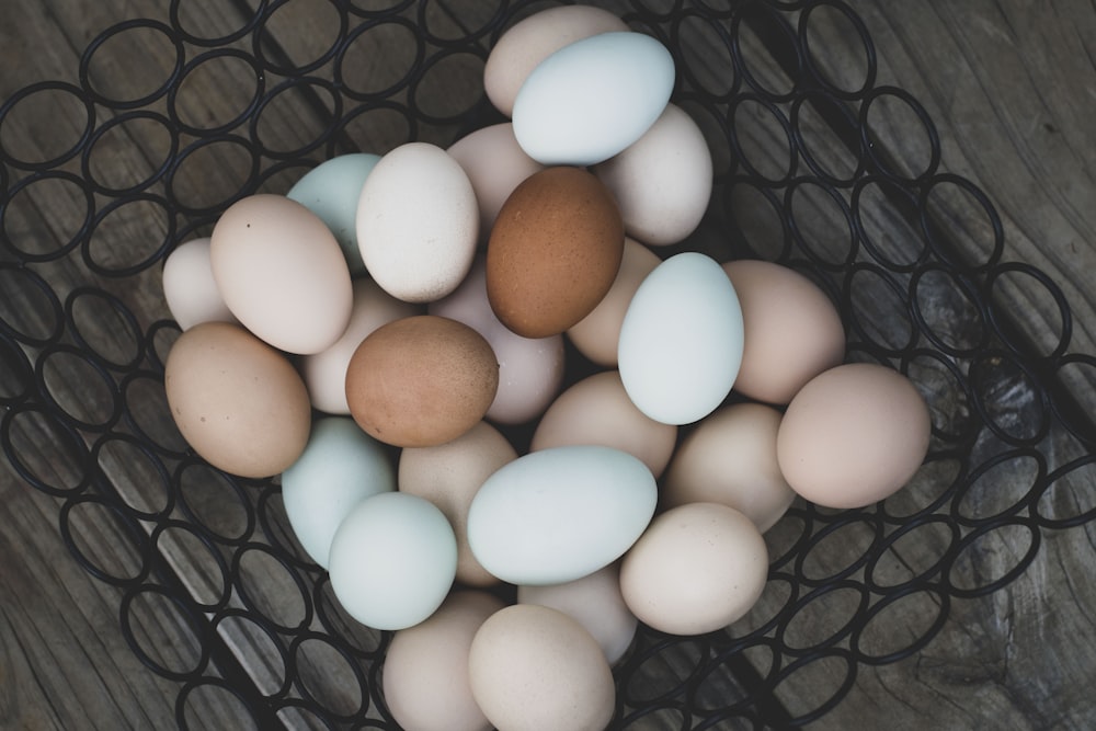 white and brown eggs on black metal basket