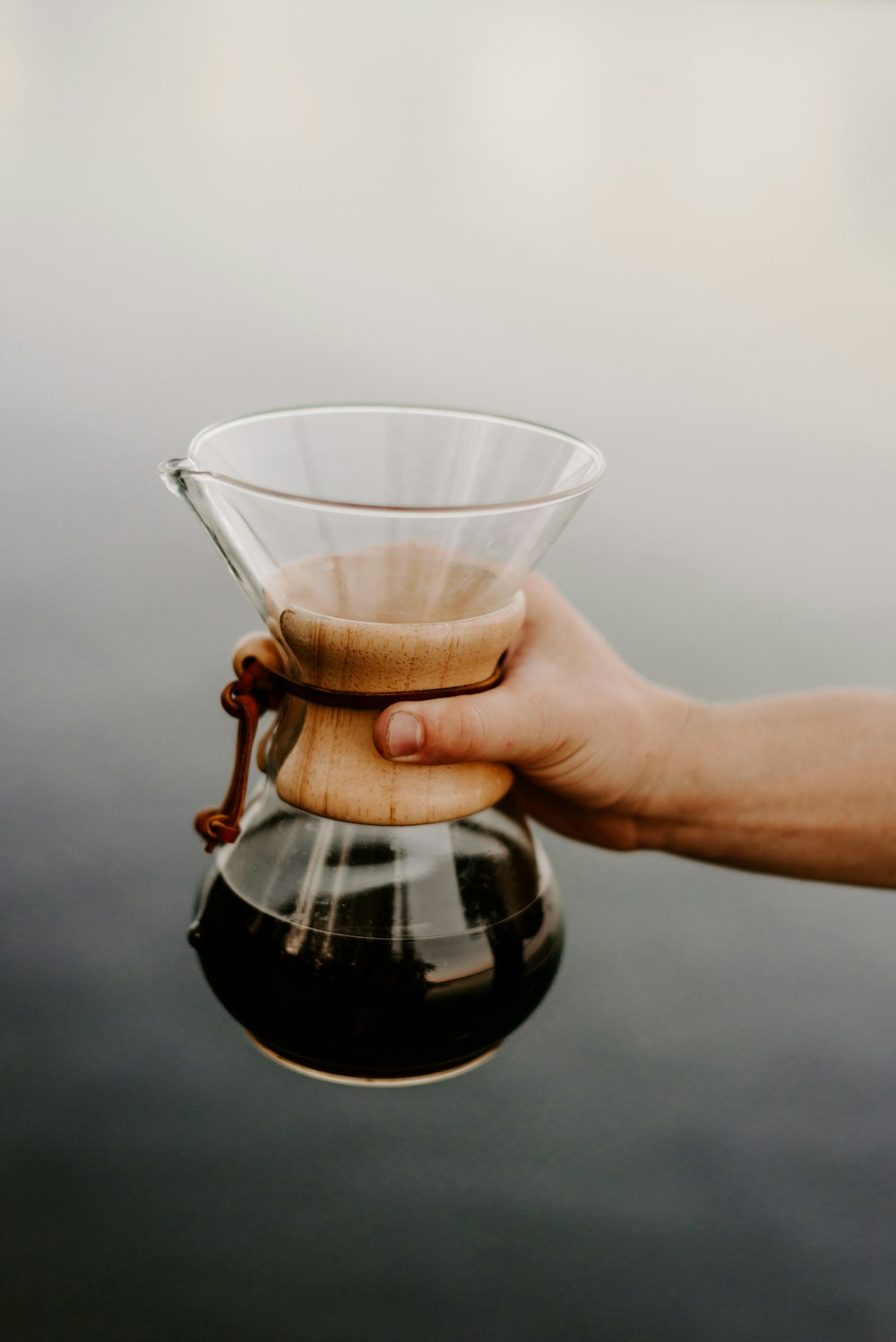 person pouring black liquid on clear drinking glass