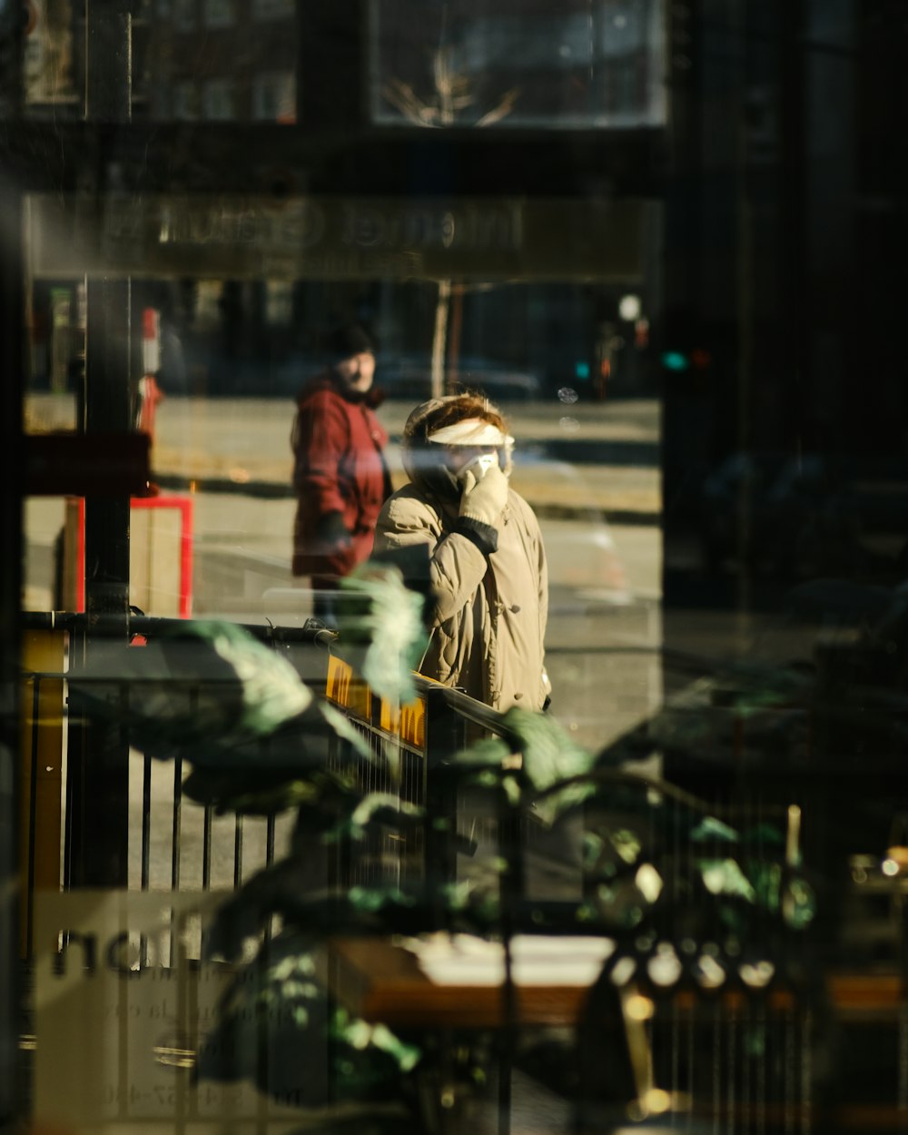 woman in brown coat standing in front of glass window