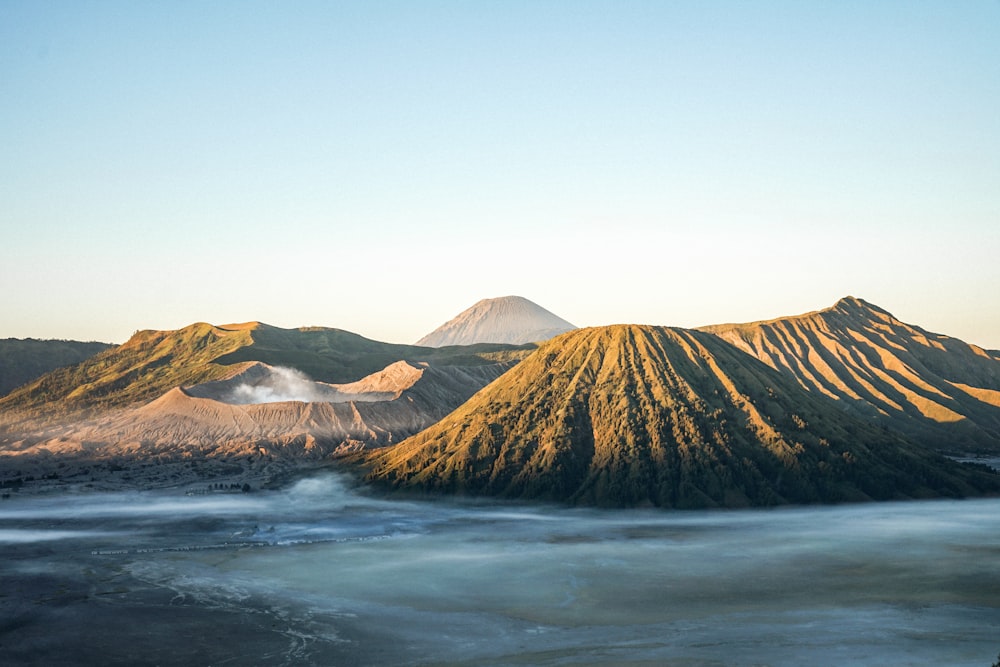 日中の水域近くの茶色の山