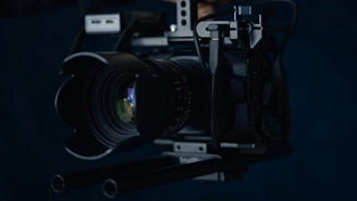Cinematic close-up of a professional videographer adjusting a camera lens against a dark, moody backdrop.