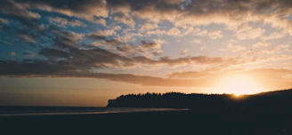 A serene beach sunset with golden hues blending into a clear blue sky, symbolizing the essence of Lume Skye Travel.