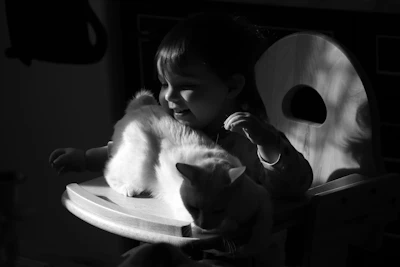 grayscale photo of girl kissing cat