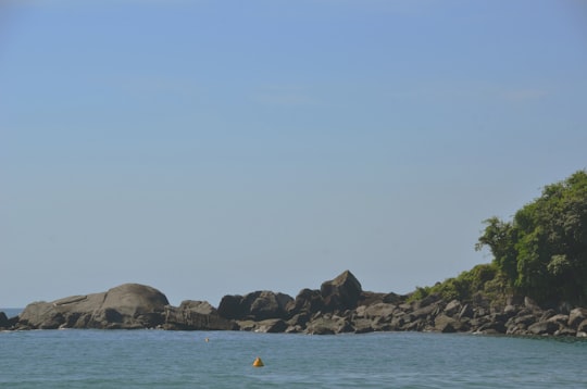 person in blue kayak on sea near brown rock formation during daytime in Ilhabela Brasil