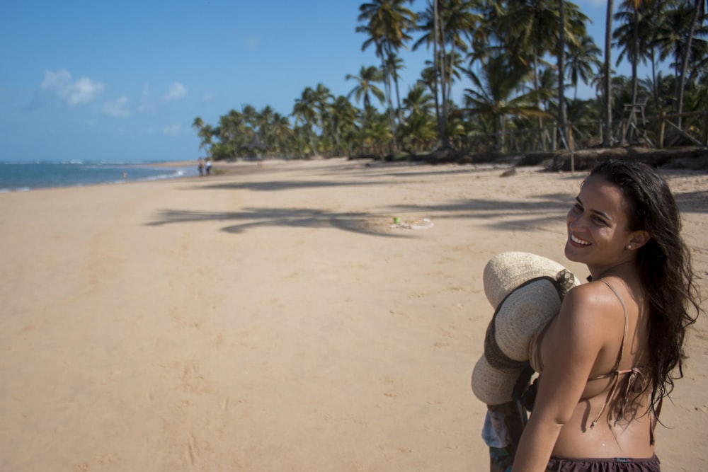 woman in white sun hat sitting on beach sand during daytime