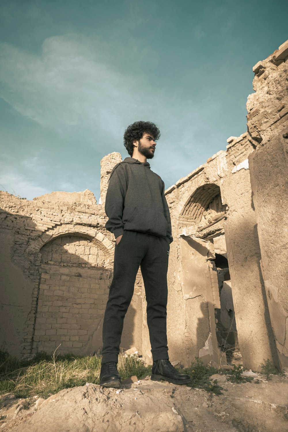 man in black suit standing near brown concrete building during daytime