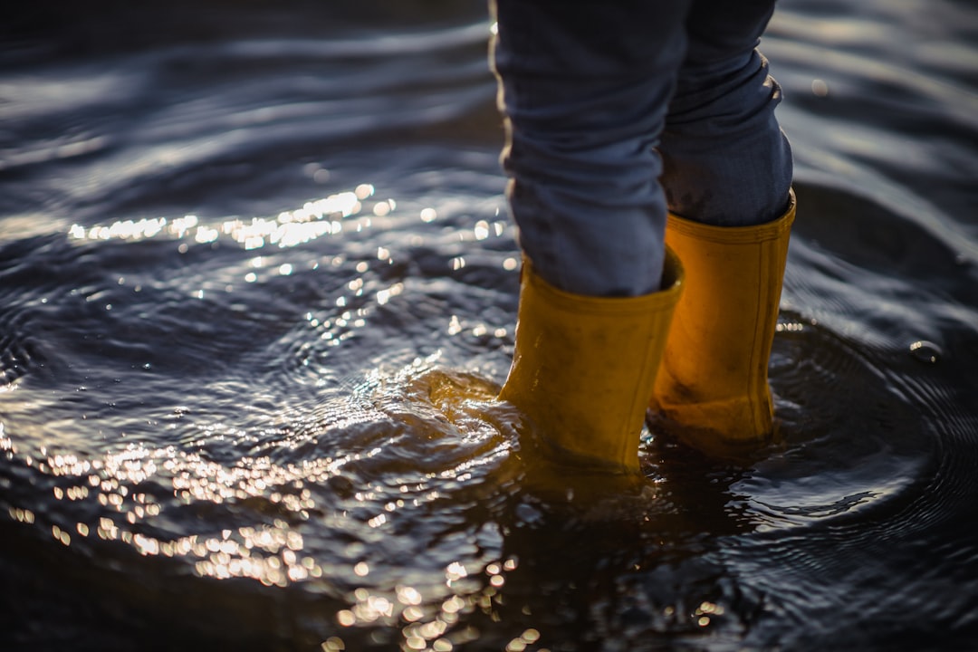 person in blue denim jeans and brown boots standing on water during daytime