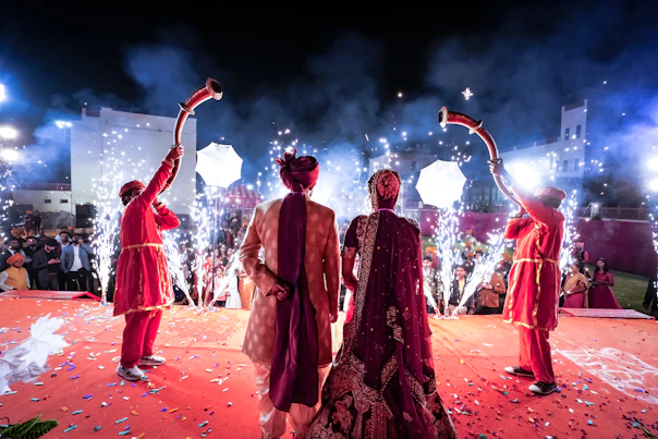 man and woman in red traditional dress dancing on brown sand during nighttime