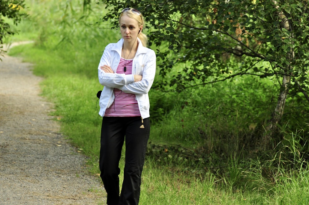 woman in white long sleeve shirt and black pants standing on pathway during daytime
