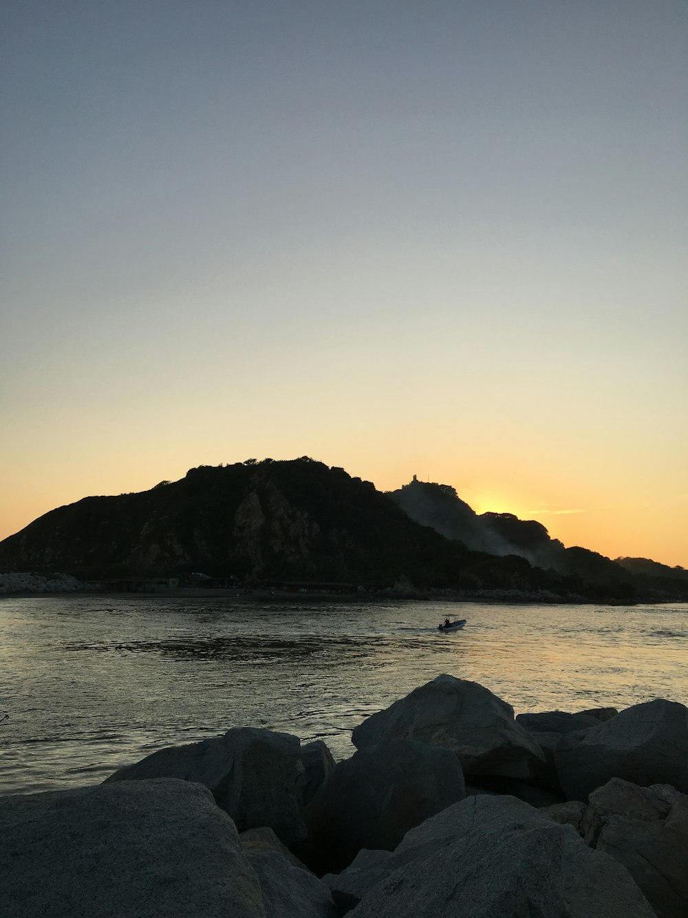 the sun is setting over a rocky beach