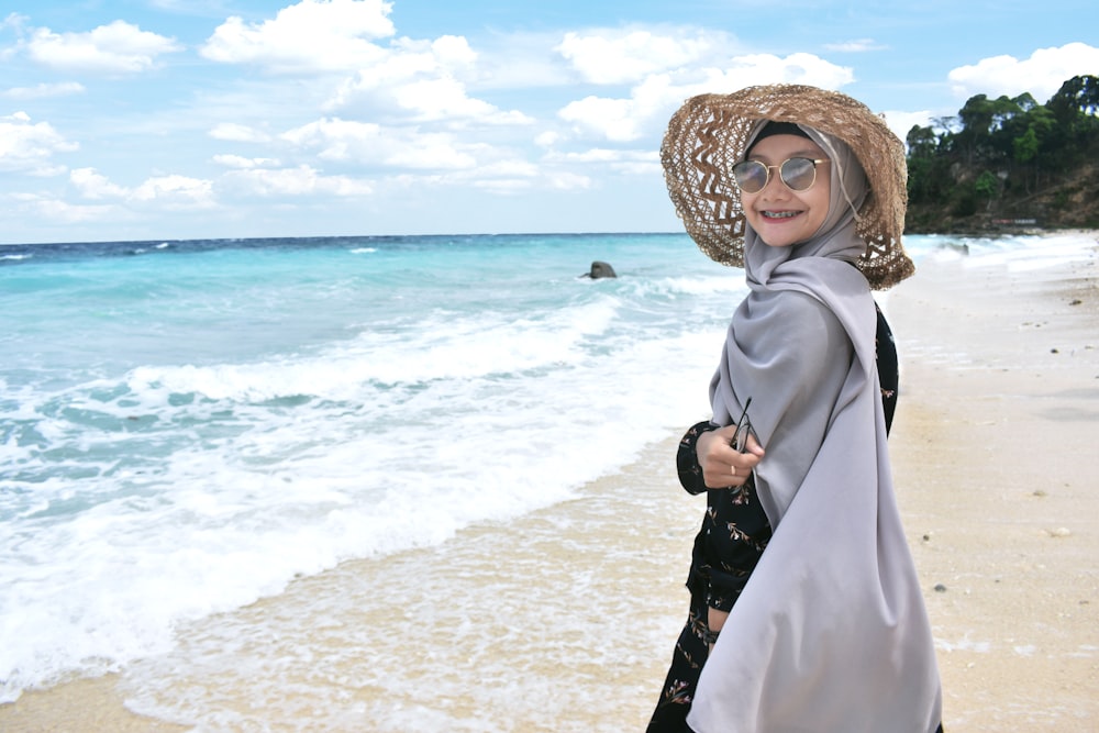 woman in gray hijab standing on beach during daytime