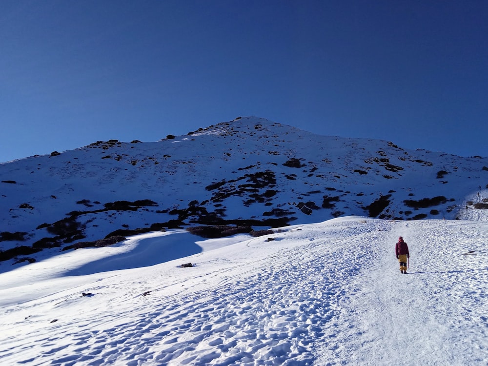 person in red jacket walking on snow covered ground during daytime