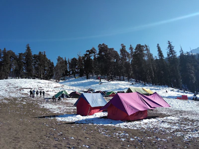 people standing near green and red tent on snow covered ground during daytime