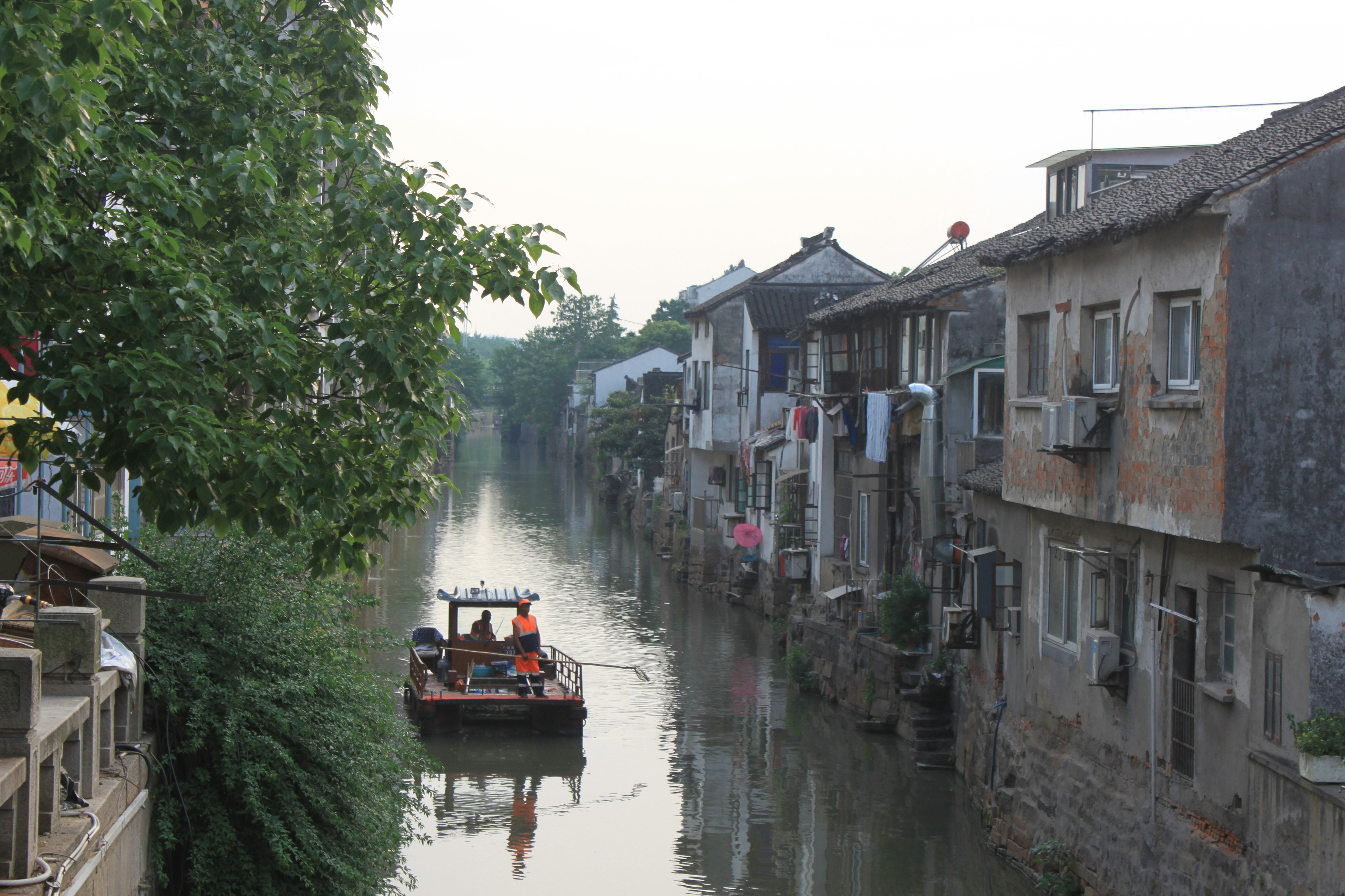 people riding boat on river between buildings during daytime