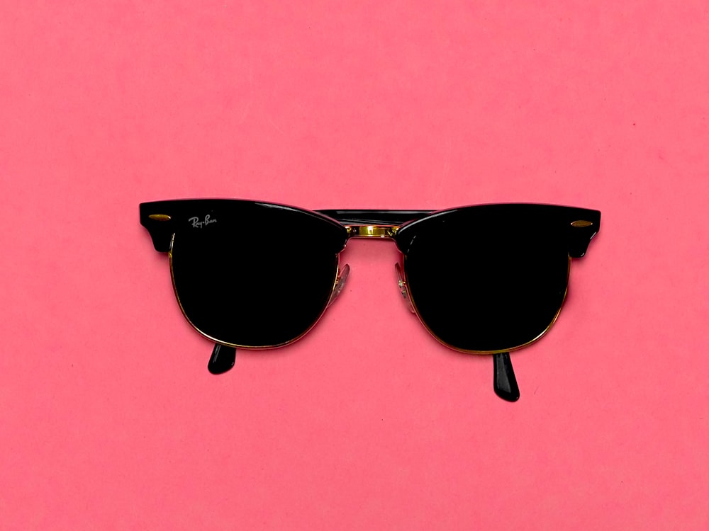 black framed sunglasses on pink surface