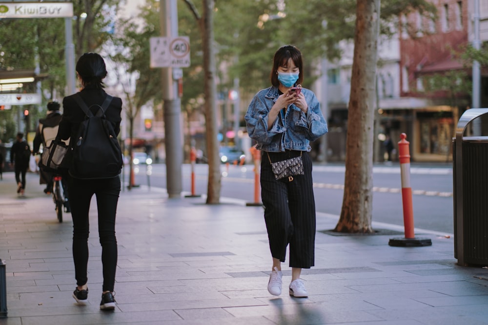 woman in black jacket and black pants standing on gray concrete floor during daytime