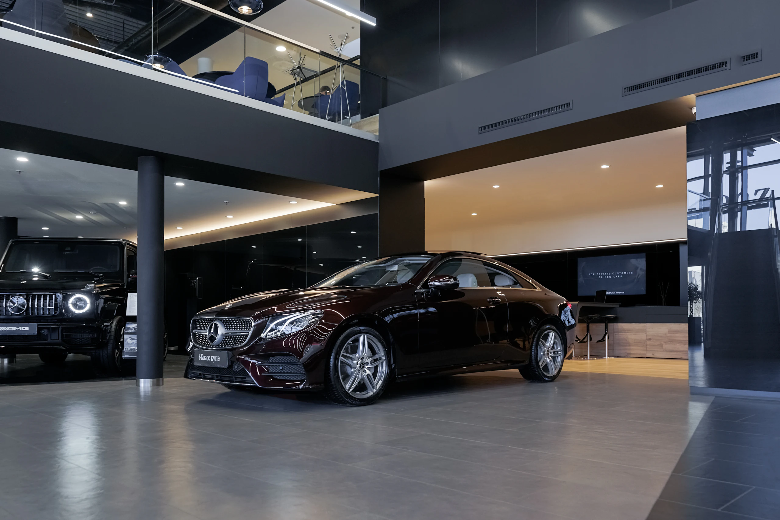 Black sports car parked on a high-gloss floor in a dark, architectural garage
