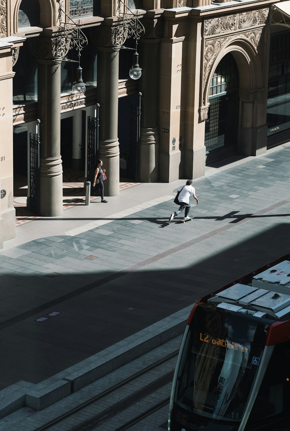 Mann in weißem Hemd und schwarzer Hose geht tagsüber auf dem Bürgersteig spazieren