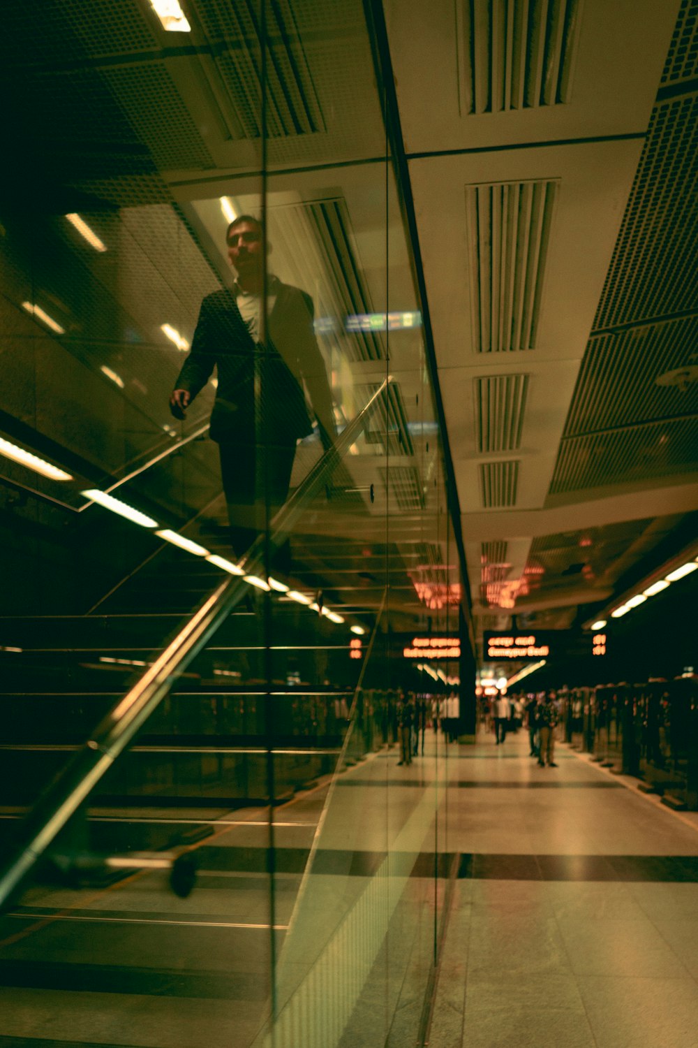 man in black suit walking on white floor tiles