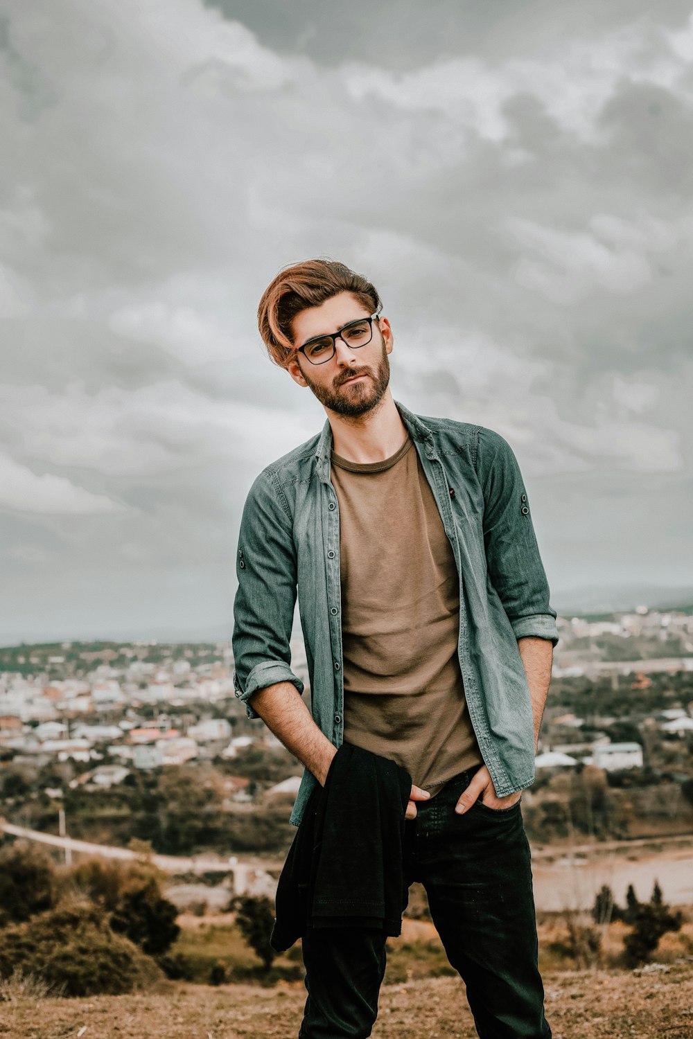 man in gray cardigan and black pants standing on the ground during daytime