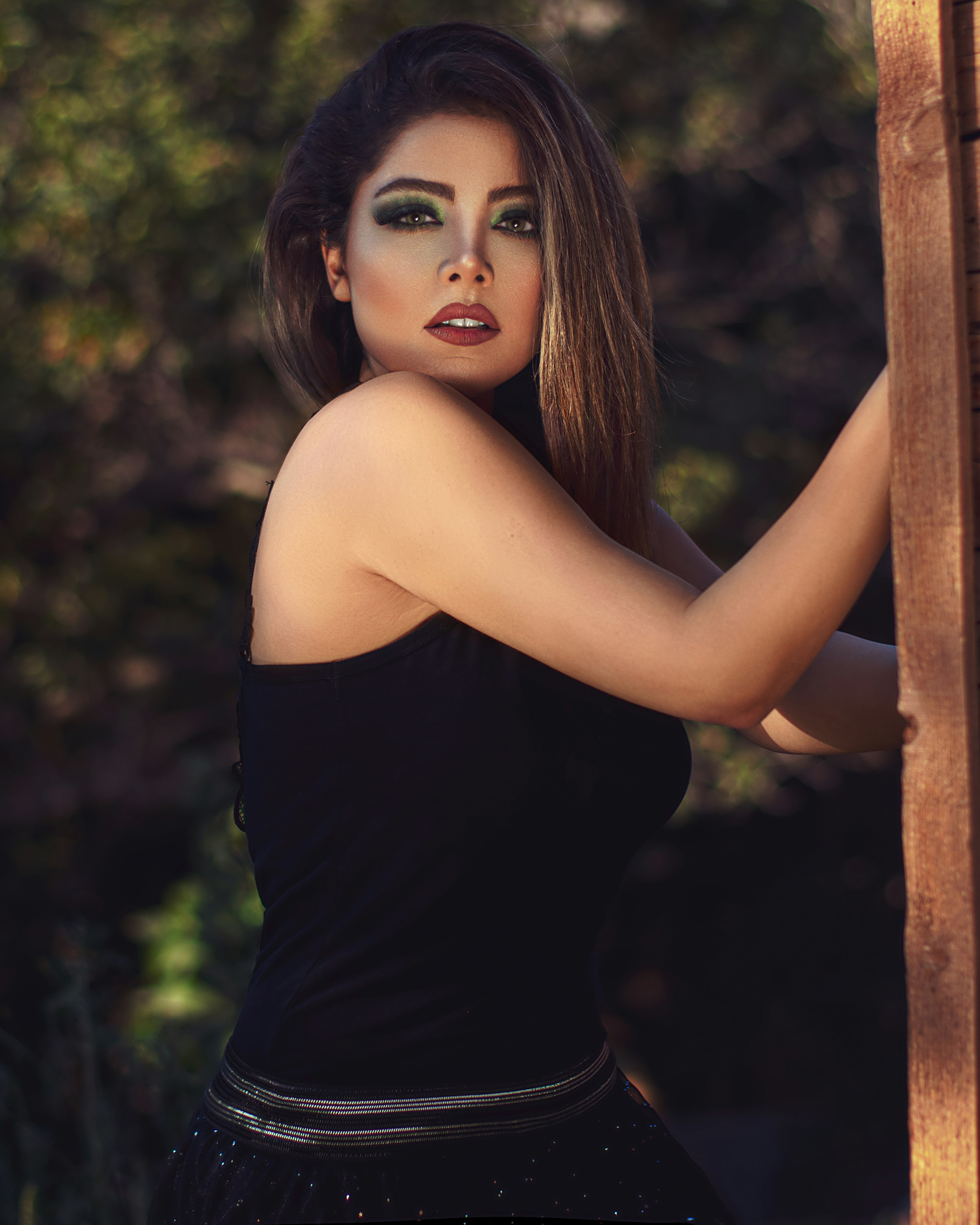 woman in black tank top leaning on brown wooden post