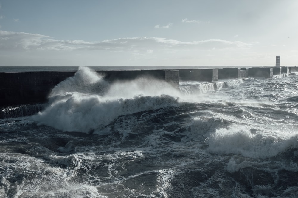 sea waves crashing on gray concrete wall during daytime