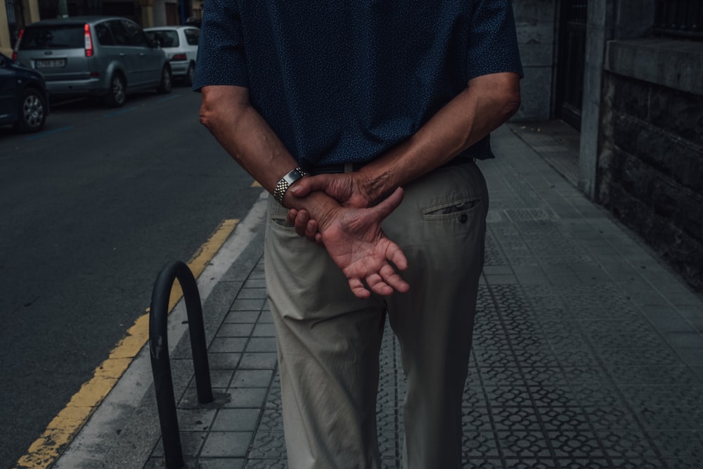man in blue polo shirt and gray pants standing on sidewalk