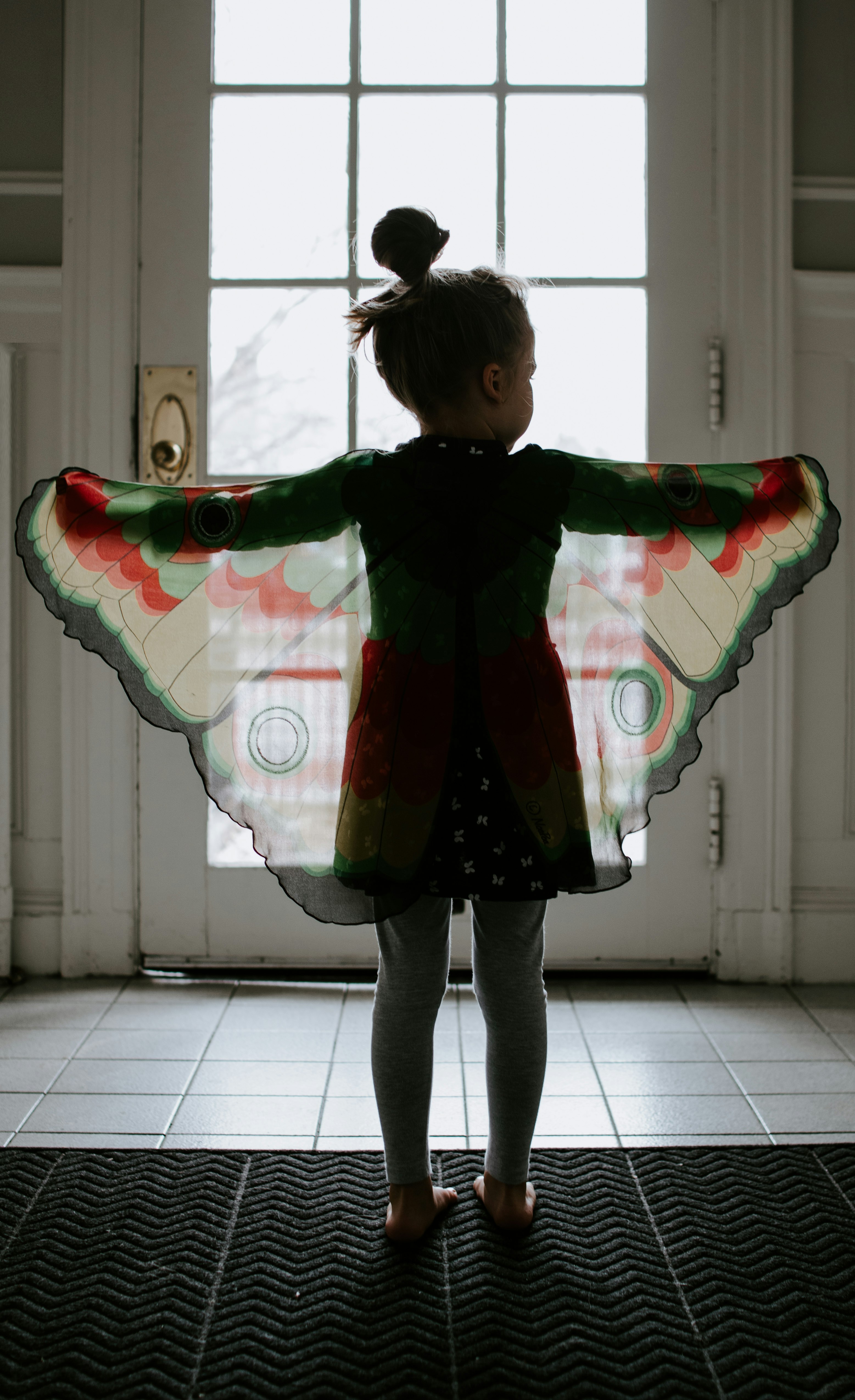 Little girl standing in a doorway with butterfly wings