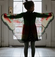 girl in black and red plaid jacket standing on white floor tiles