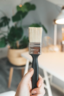 A friendly painter holding a brush standing in front of a freshly painted wall in a cozy Slavonski Brod home