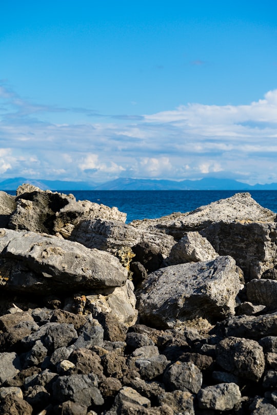 gray and black rocky shore under blue sky during daytime in Pontikonisi Greece