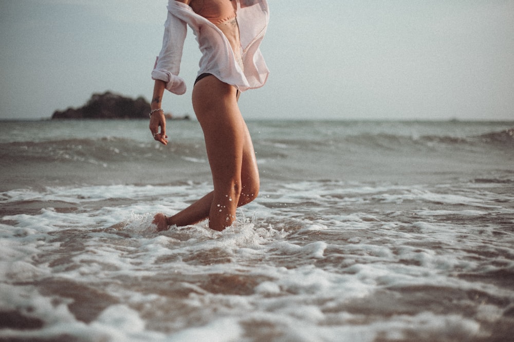 woman in white dress walking on beach during daytime