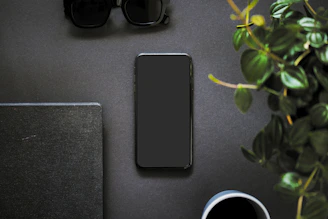 Minimalist flat lay of a smartphone turned off beside a cup of herbal tea and a notebook.
