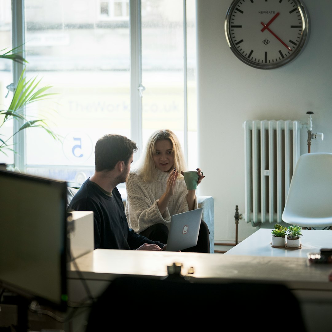 man and woman sitting on chair in front of silver macbook