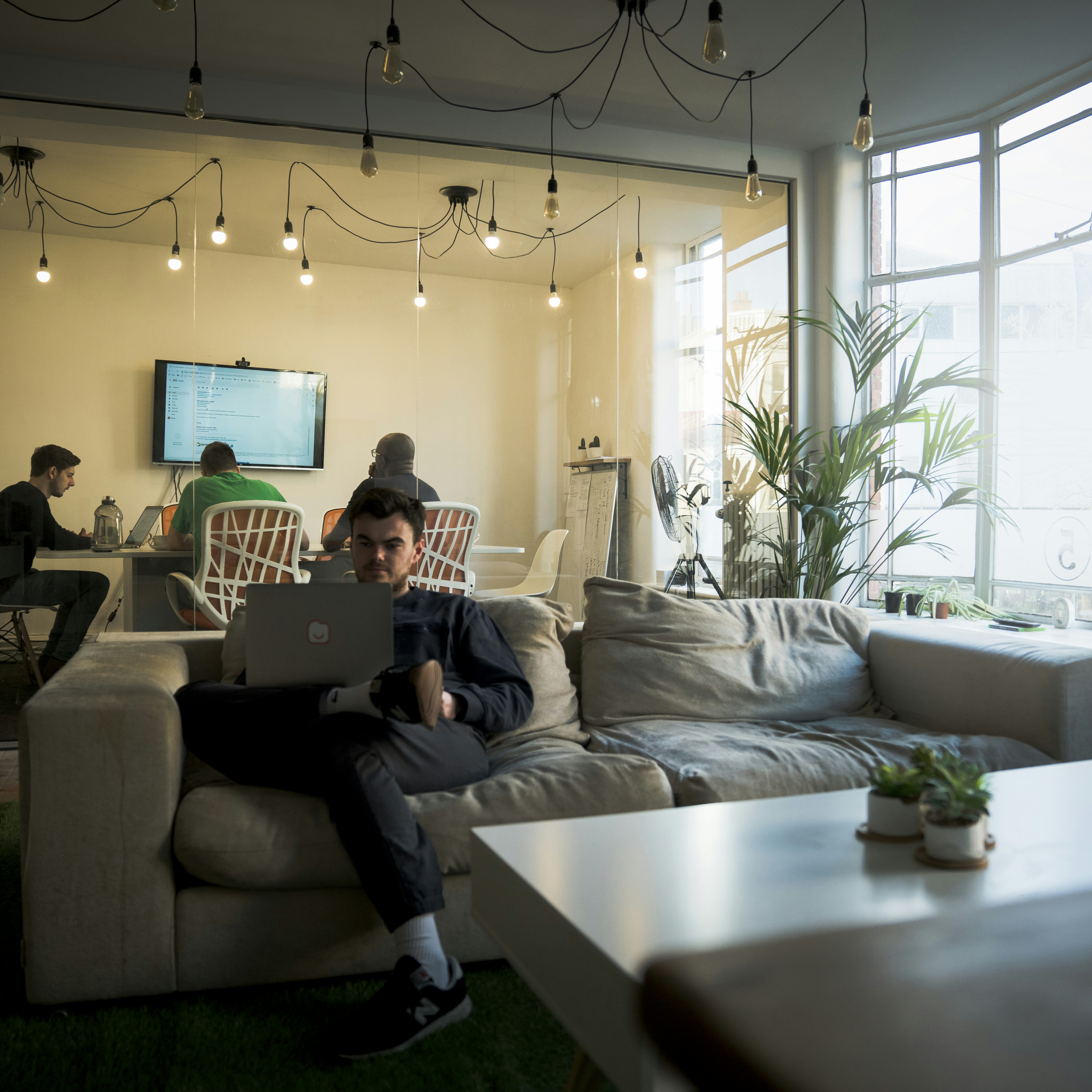 man in black t-shirt sitting on couch using macbook