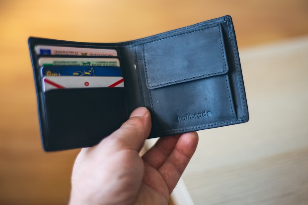 black leather bifold wallet on persons hand
