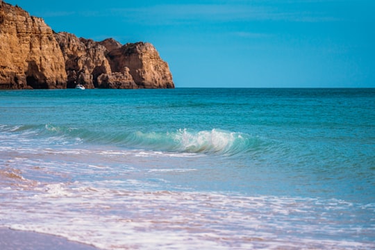 brown rock formation on sea during daytime in Lagos Portugal