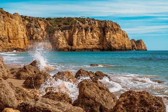 brown rock formation on sea during daytime in Lagos Portugal