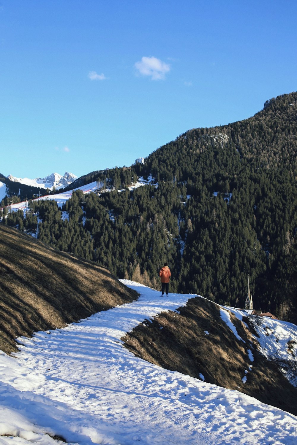 person in red jacket standing on snow covered ground during daytime