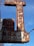 A rusted vintage sign with faintly visible words reading 'AUTO PARTS' and 'AUTO PAINTS', accompanied by some old light fixtures and electric wiring against a clear blue sky.