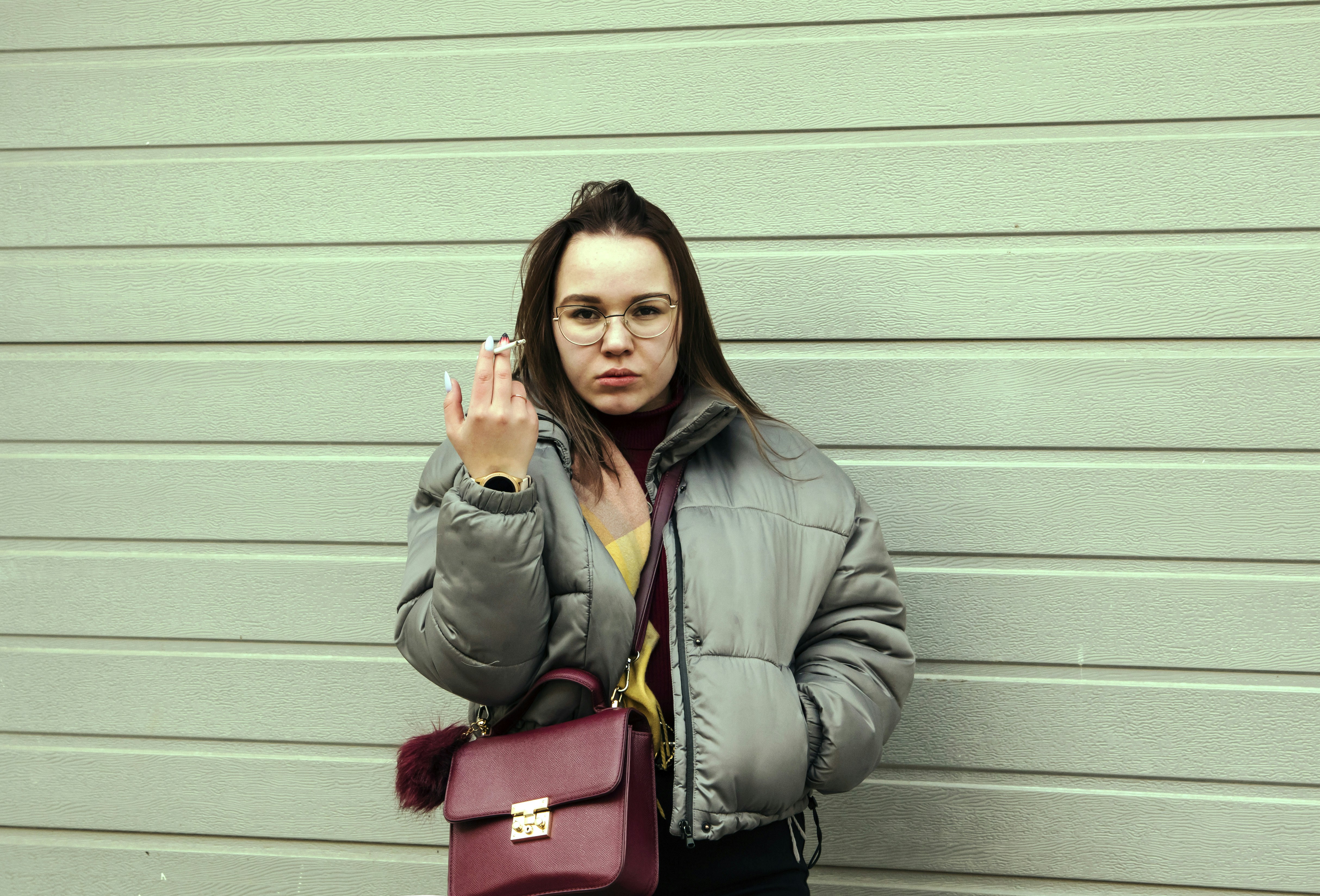 woman in gray coat holding red leather handbag
