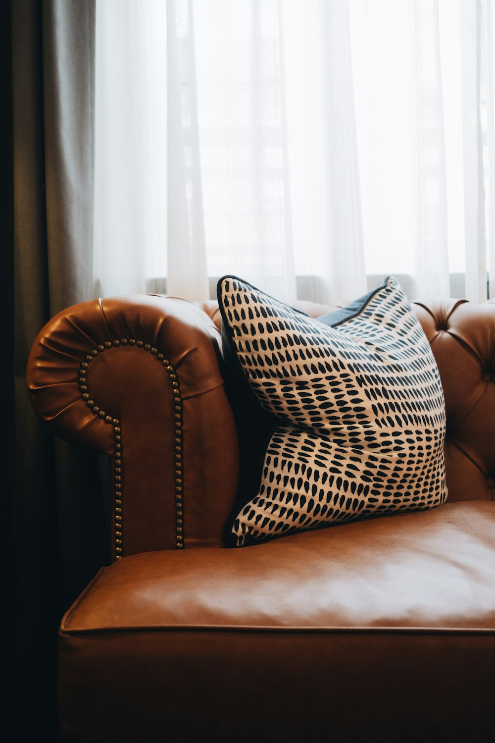brown and white throw pillow on brown leather couch