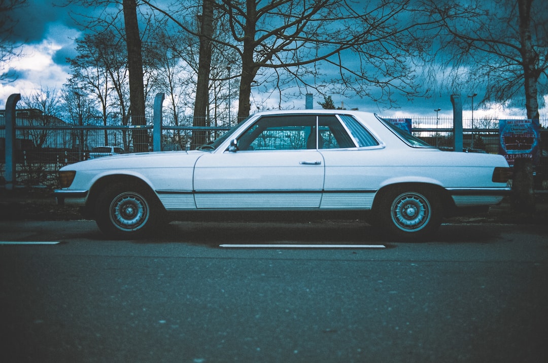 white sedan parked on gray asphalt road during daytime