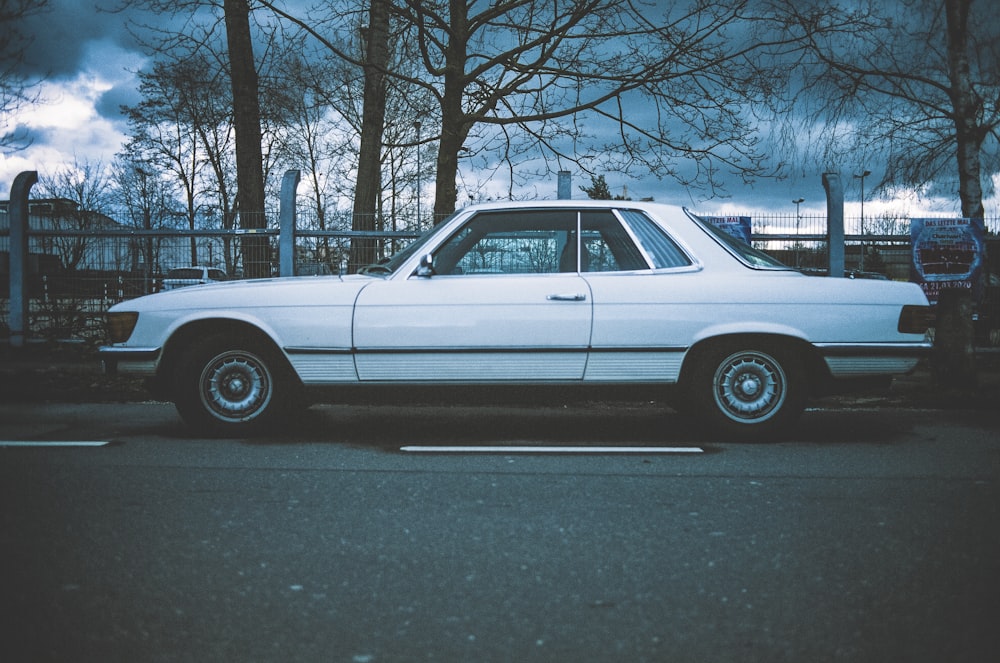 white sedan parked on gray asphalt road during daytime