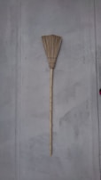 Traditional broom leaning against a rustic wall, representing durability and simplicity.