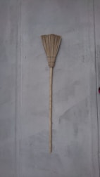 Traditional brooms with natural straw bristles leaning against a rustic wall.