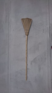 Traditional brooms with natural straw bristles leaning against a rustic wall.