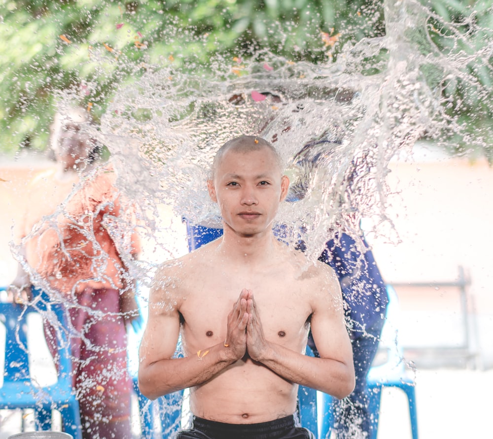 topless boy in blue shorts standing on water fountain during daytime