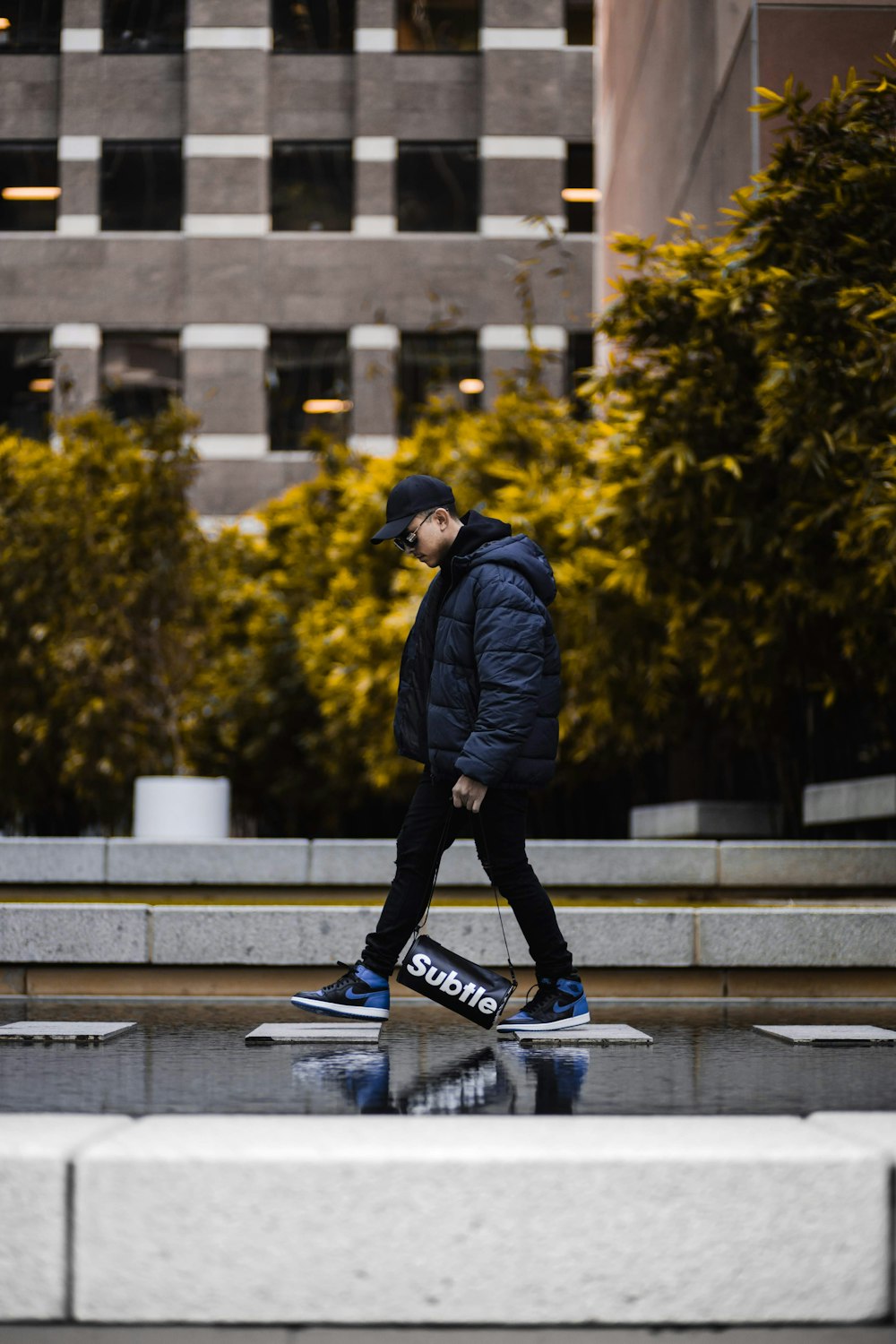 man in black jacket and blue pants riding blue and black skateboard during daytime