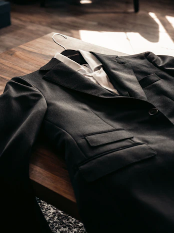 A sleek, minimalist men's outfit laid out on a wooden table with natural light highlighting textures.